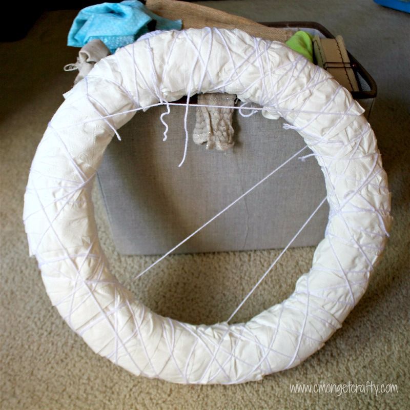 Use toilet paper, paper, and yarn to make your own DIY Toilet Paper Mummy wreath! #halloween #diy #mummywreath #diyhalloweendecor #notsoscaryhalloween #cheapcrafts #toiletpapermummywreah #diyhalloween #diywreath #mummy #mummywreath #halloweendoor #cmongetcrafty