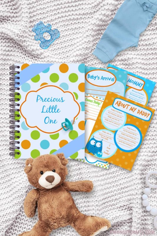 white knit blanket background, flatlay with brown teddy bear, blue bear teething ring, blue baby pants, and spiral bound baby book and loose pages in blue and orange theme