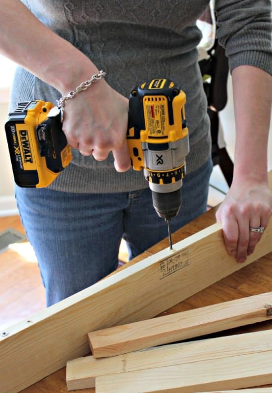 Woman drilling hole in wood for DIY picture ledge building