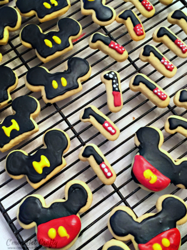 Mickey mouse themed cookies in black and red icing laying on a cooling rack