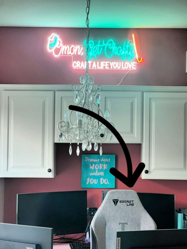 IMG_8191 1 - C'mon Get Crafty white cabinet office space with pink walks and a chandelier - black arrow graphic overlaid to point towards grey office chair