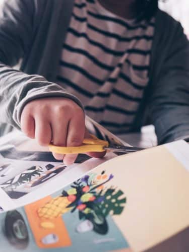 xavi-cabrera-tVjxxhF3XsA-unsplash - C'mon Get Crafty hands using scissors to cut images from magazine