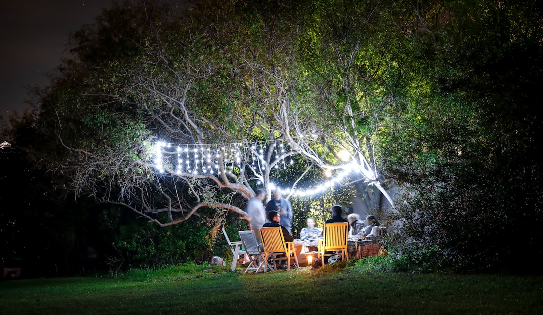 Photo by Garth Manthe - C'mon Get Crafty people sitting on brown wooden chairs under green trees during daytime