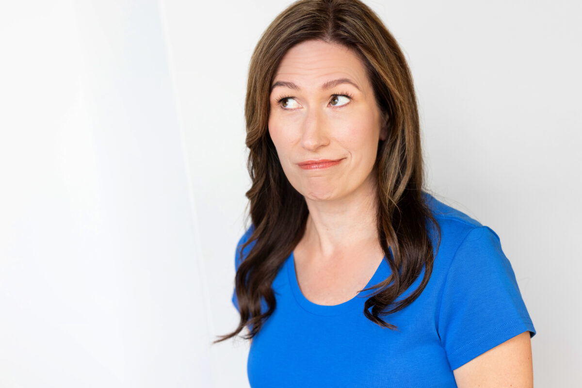 Megan in a blue shirt with a wry smile, looking off camera