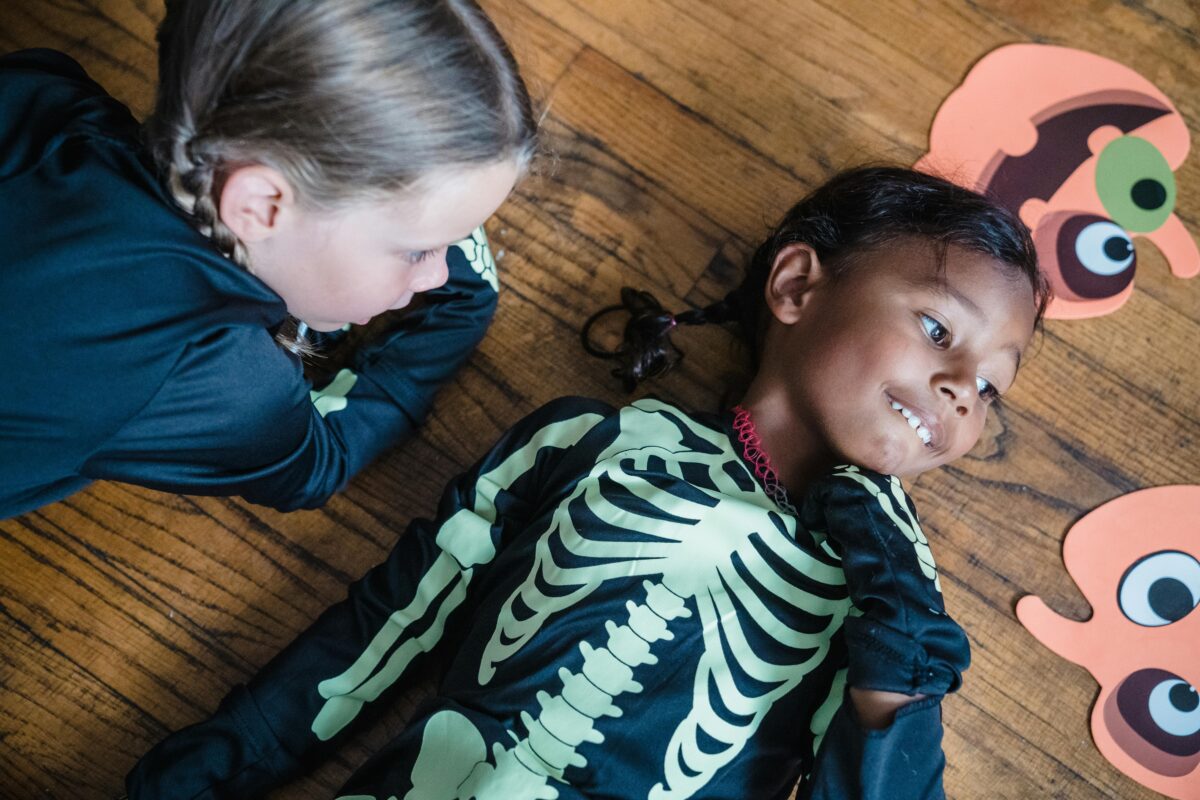 Young girls laying down on floor on halloween costumes