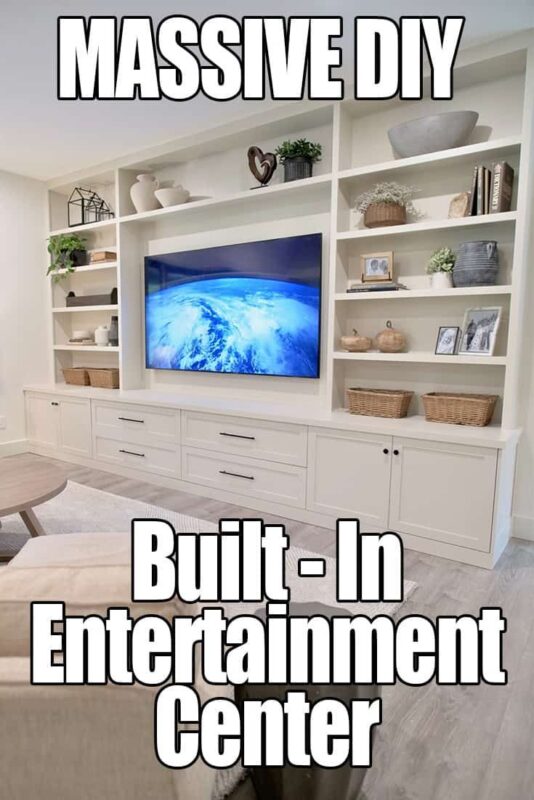 6803eb413796a151bed370f3d939529f - C'mon Get Crafty Large DIY built-in entertainment center with shelving, storage cabinets, and a mounted TV, decorated with plants, baskets, and books — modern living room storage solution.
